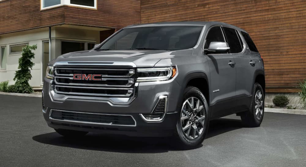 A silver 2022 GMC Acadia is shown from the front parked in front of a building.