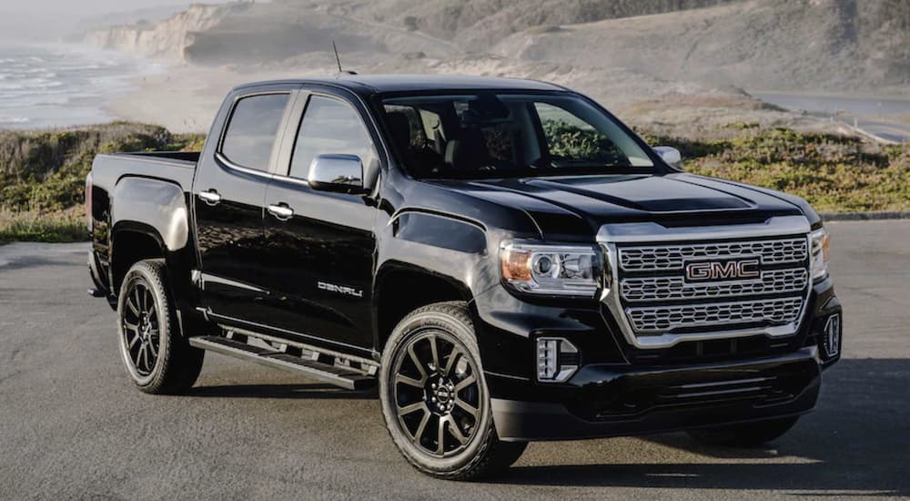 A black 2022 GMC Canyon is shown from the side parked in front of a mountain.