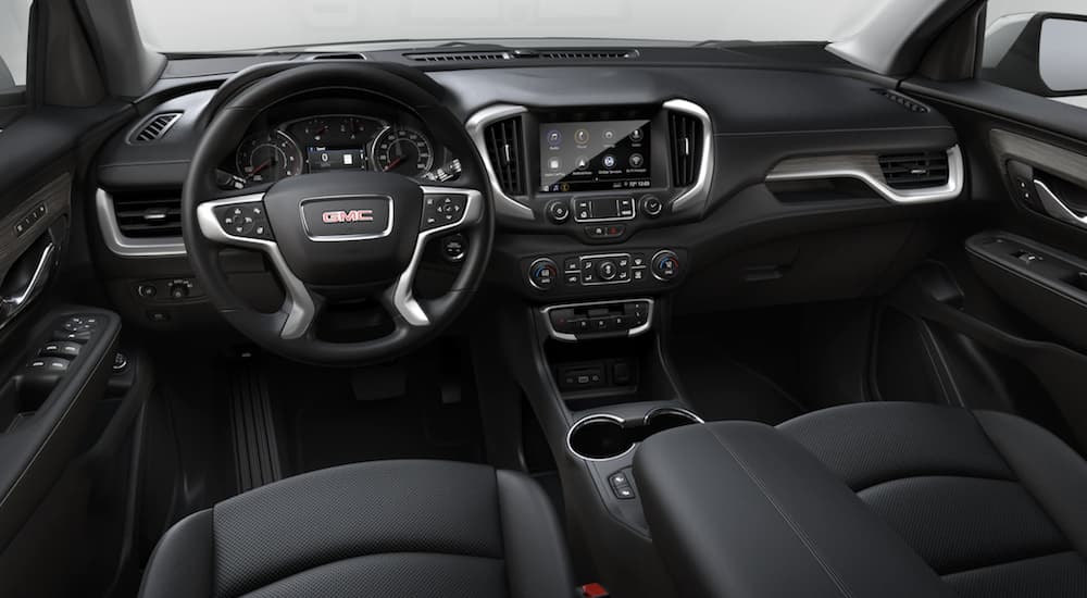 The black interior of a 2022 GMC Terrain SLT shows the steering wheel and infotainment screen.