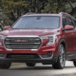 A red 2022 GMC Terrain SLT is shown from the front driving on an open road.