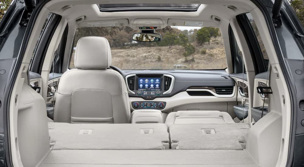 The white interior of a 2022 GMC Terrain SLT shows the back seats folded down to reveal a large cargo space.