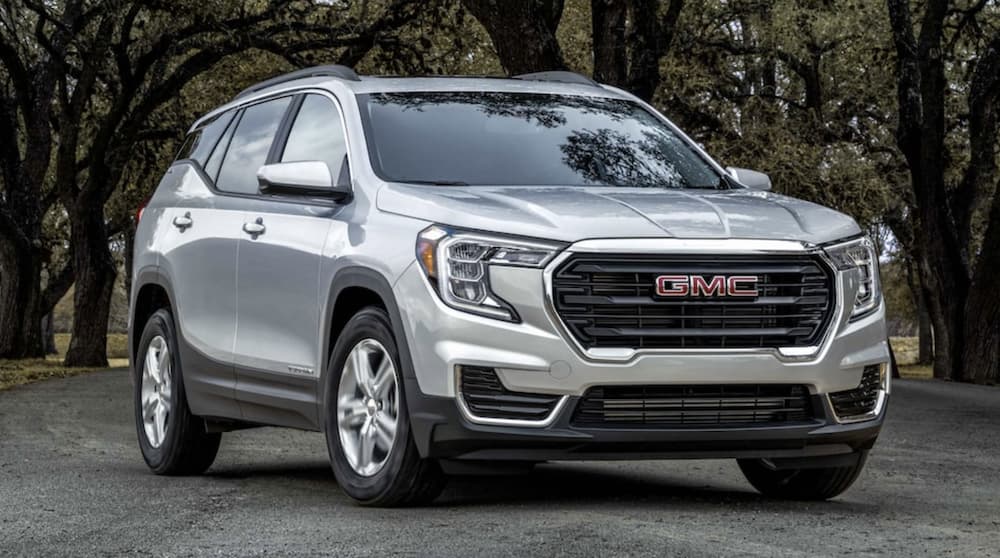 A silver 2022 GMC Terrain is shown parked in front of the woods during a 2022 GMC Terrain vs 2022 Jeep Cherokee comparison.