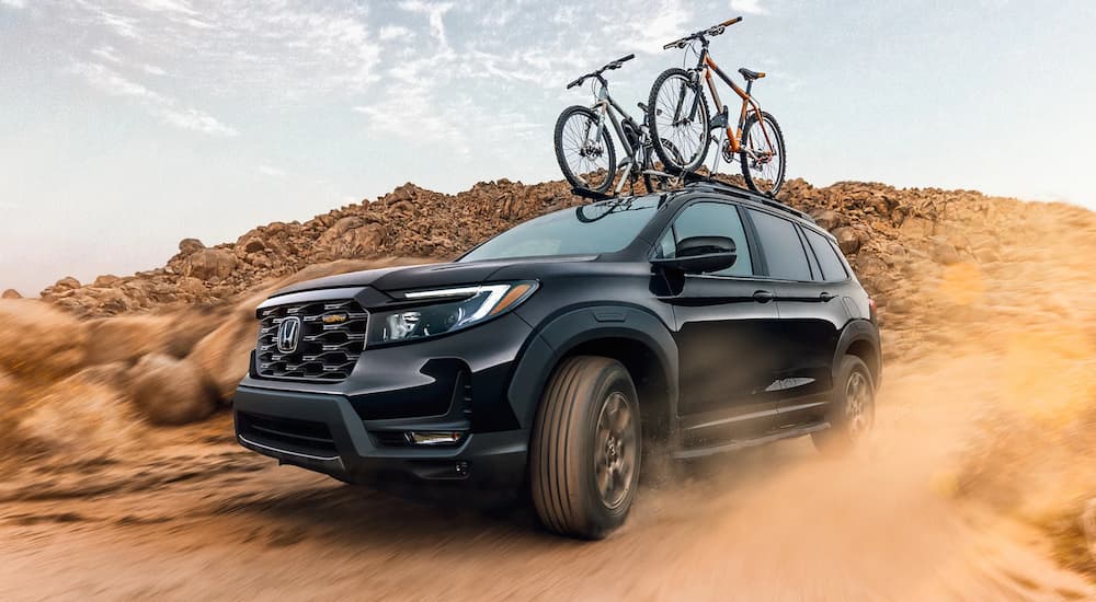A black 2022 Honda Passport is shown from the front at an angle while it drives through the desert.