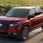 A red 2022 Honda Ridgeline Sport is shown driving on a dirt road during a 2022 Honda Ridgeline vs 2022 Chevy Colorado comparison.