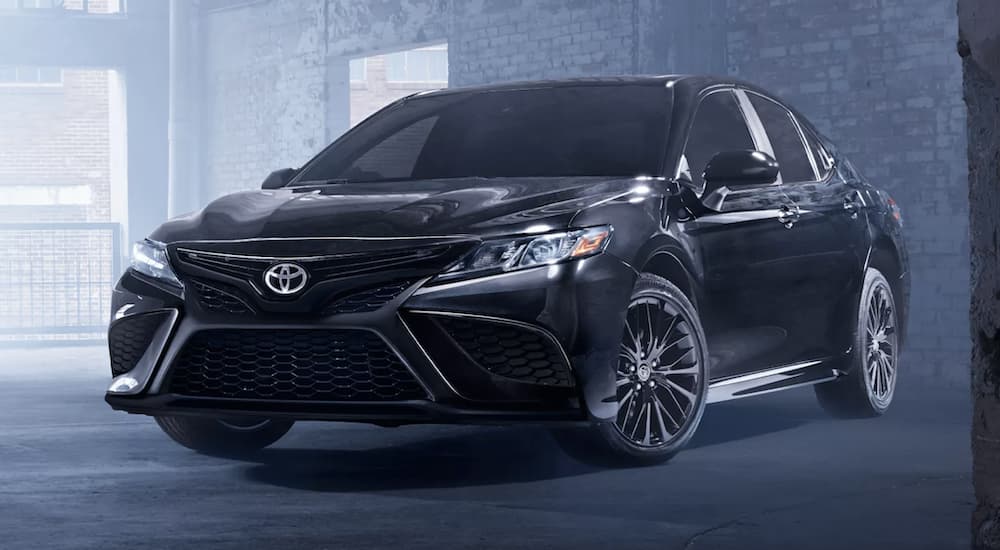 A black 2022 Toyota Camry SE is shown parked in a warehouse.