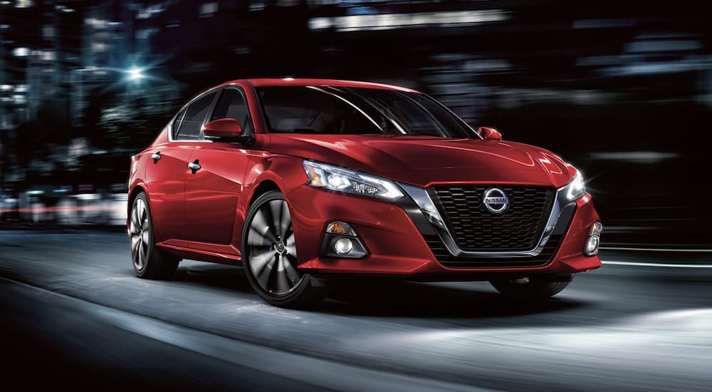 A red 2022 Nissan Altima is shown from the front driving through a city.