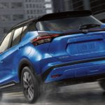 A blue 2022 Nissan Kicks is shown from the rear driving through a city.
