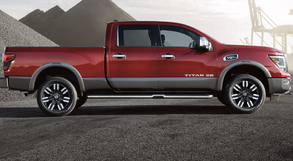 A red 2022 Nissan Titan XD is shown from the side parked at a sand lot.