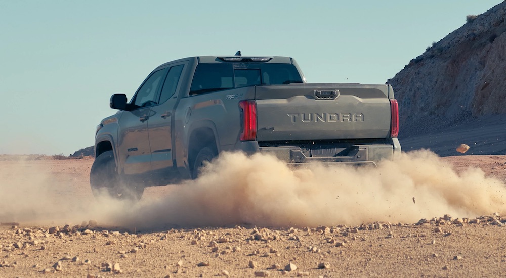 A grey 2022 Toyota Tundra is shown from the rear while kicking up dust in a desert.