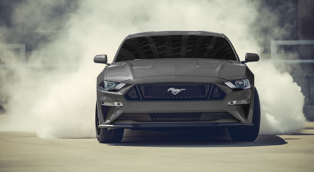 A grey 2019 Ford Mustang GT is shown from the front doing a burnout.