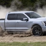 A silver 2022 Ford F-150 Lightning is shown from the side on a dirt trail after leaving a Ford F-150 dealer.