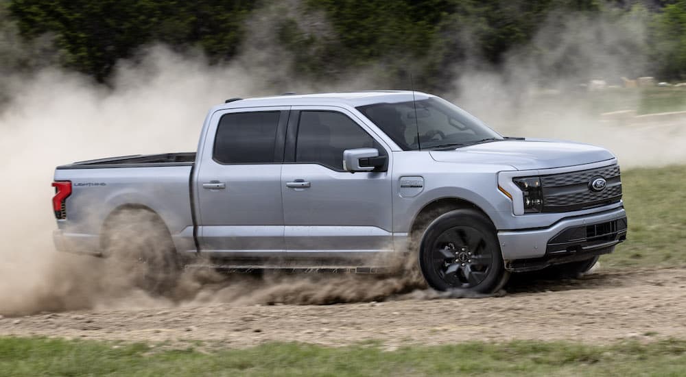 A silver 2022 Ford F-150 Lightning is shown from the side on a dirt trail after leaving a Ford F-150 dealer.