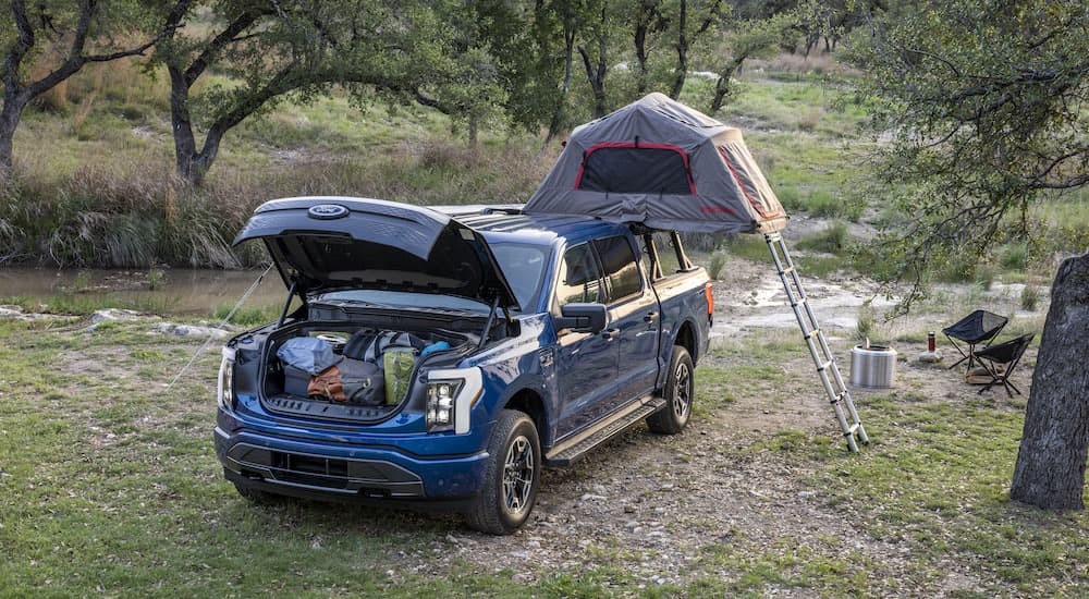 A blue 2022 Ford F-150 Lightning is shown from the front while set up for overlanding.