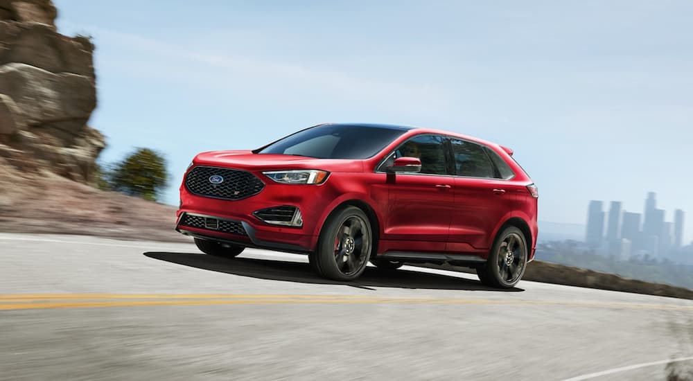 A red 2022 Ford Edge is shown from the front at an angle while it drives down the road.
