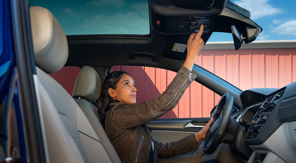 A woman is shown opening the sunroof in a 2022 Volkswagen Tiguan SEL-R Line at a VW Tiguan dealer.