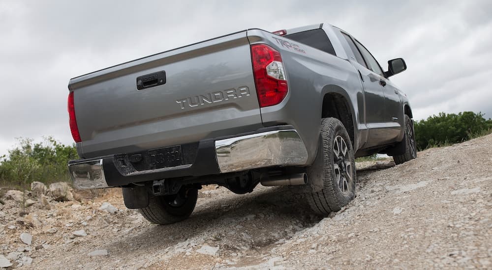 A grey 2019 Toyota Tundra is shown from the rear off-roading on a sand hill.