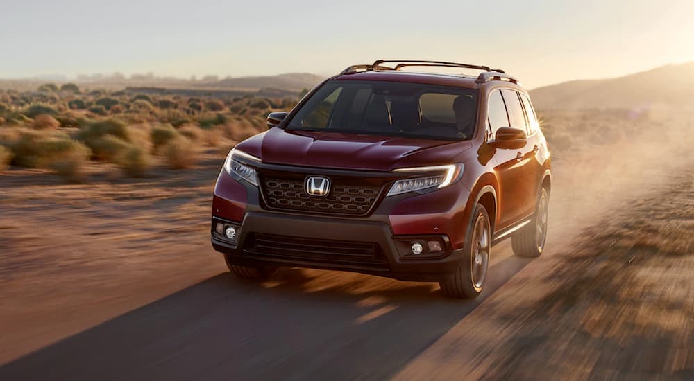 A red 2020 Honda Passport is shown from the front on a dirt road.