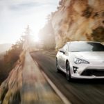 A white 2020 Toyota GT86 is shown from the front while driving down the road after the owner searched 'used car dealer'.