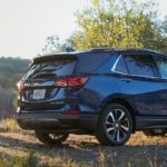 A blue 2022 Chevy Equinox is shown from the side parked near a hiking trail.