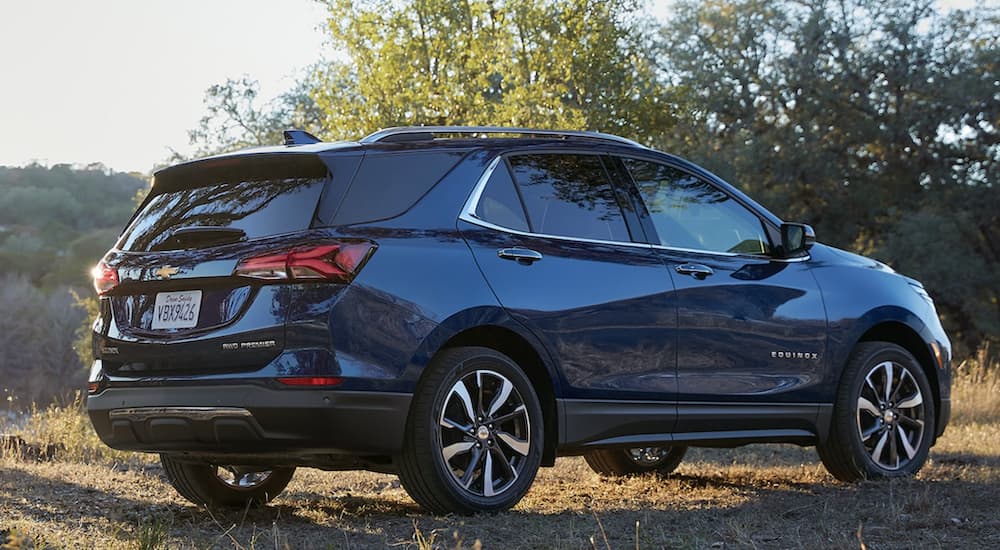 A blue 2022 Chevy Equinox is shown from the side parked in a field during a 2022 Chevy Equinox vs 2022 Ford Escape comparison.