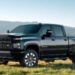 A black 2022 Chevy Silverado 2500HD Custom is shown parked on a grassy field.