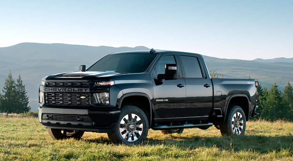 A black 2022 Chevy Silverado 2500HD Custom is shown parked on a grassy field.