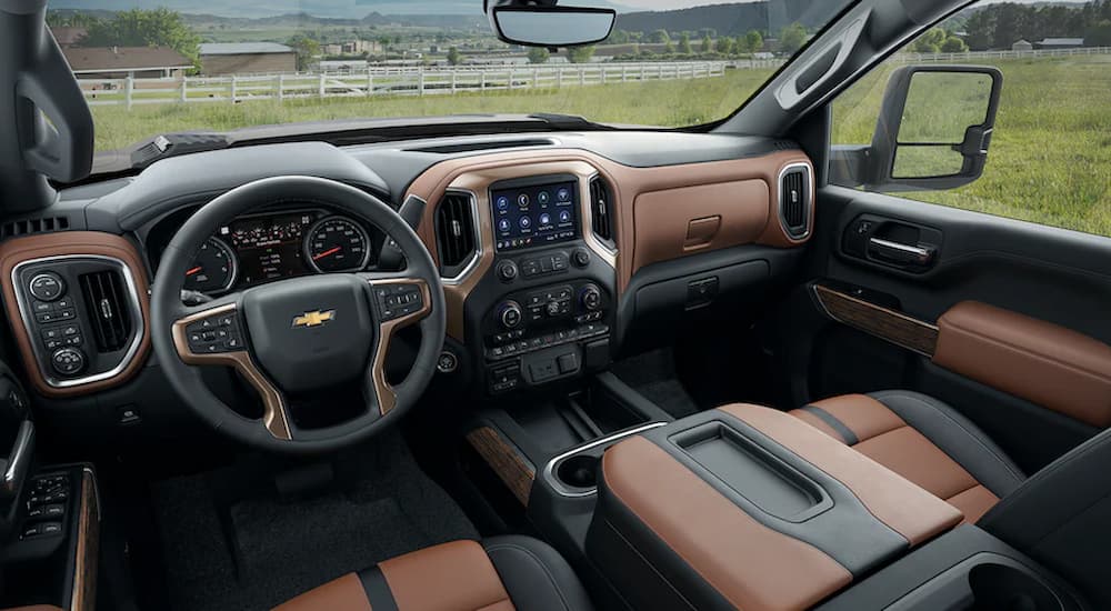 The black and brown interior of a 2022 Chevy Silverado 2500HD Custom shows the steering wheel and center console.