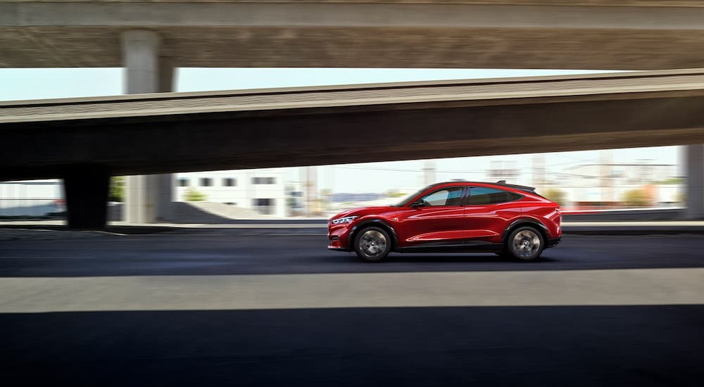 A red 2022 Ford Mustang Mach-E is shown from the city driving on a highway.