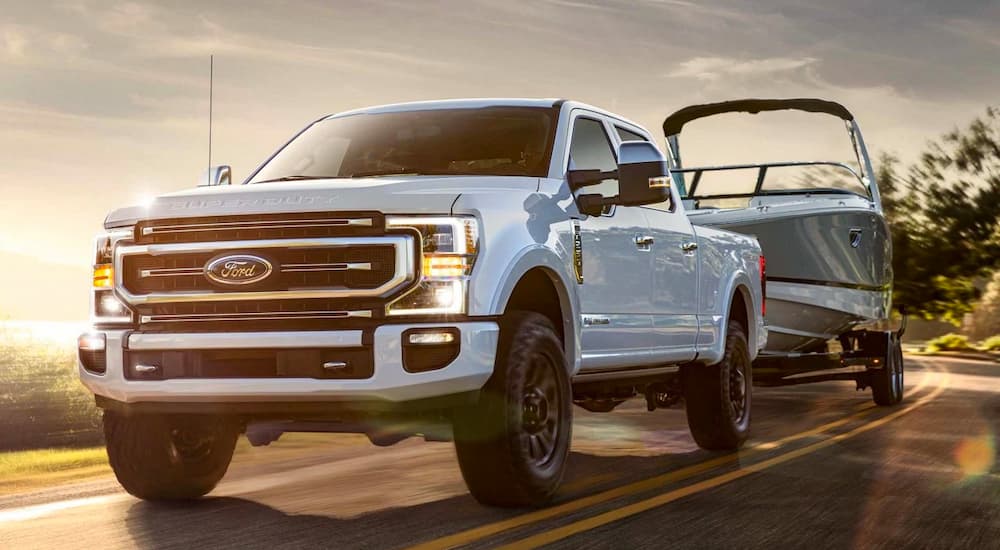 A white 2022 Ford F-350 Super Duty is shown towing a boat.