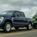 A blue 2022 Ford F-350 Super Duty is shown towing a tractor after leaving a 2022 Ford Super Duty dealer.