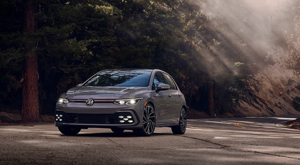 A grey 2022 Volkswagen Golf GTI Autobahn is shown from the front at an angle on a forest road.