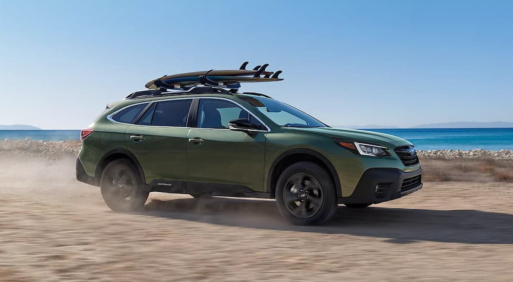A green 2022 Subaru Outback Onyx Edition XT is shown driving on a road near a beach.