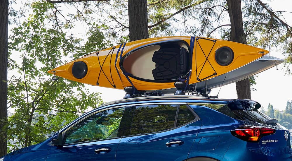 A close up of a yellow kayak on top of a blue 2022 Buick Encore GX is shown.
