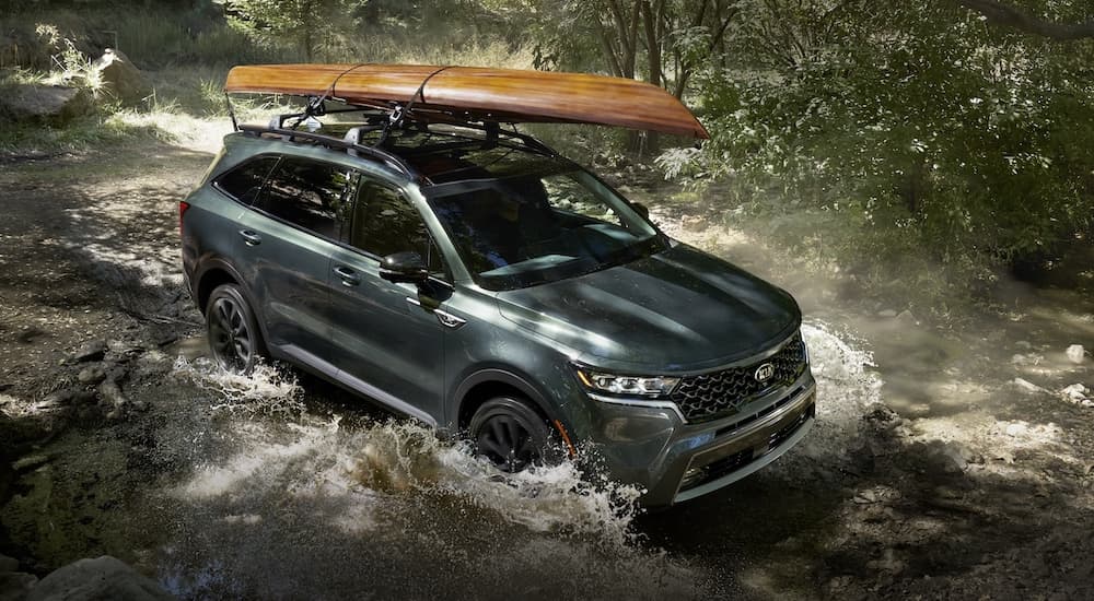A green 2021 Kia Sorento X-Line is shown driving through water after visiting a Kia dealer.