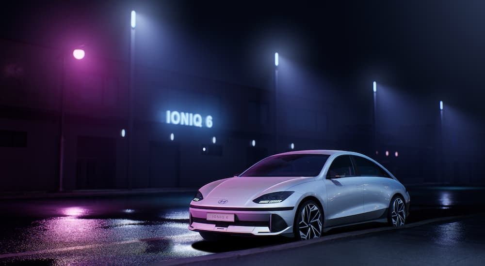 A white 2023 Hyundai Ioniq 6 is shown from the front at an angle on a dark stage.