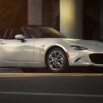 A white 2022 Mazda MX-5 is shown on a city street.