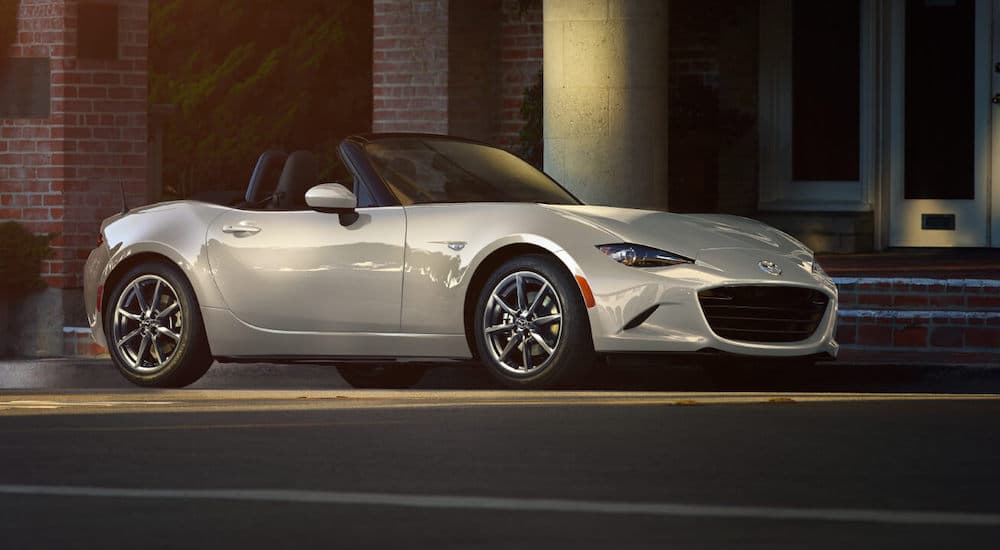 A white 2022 Mazda MX-5 is shown on a city street.