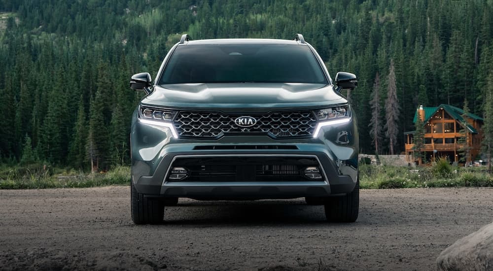A dark green 2021 Kia Sorento X-Line is shown parked near a cabin in the woods.