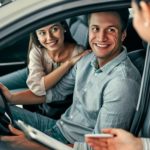 A couple is shown speaking to a saleswoman about how to sell their car.