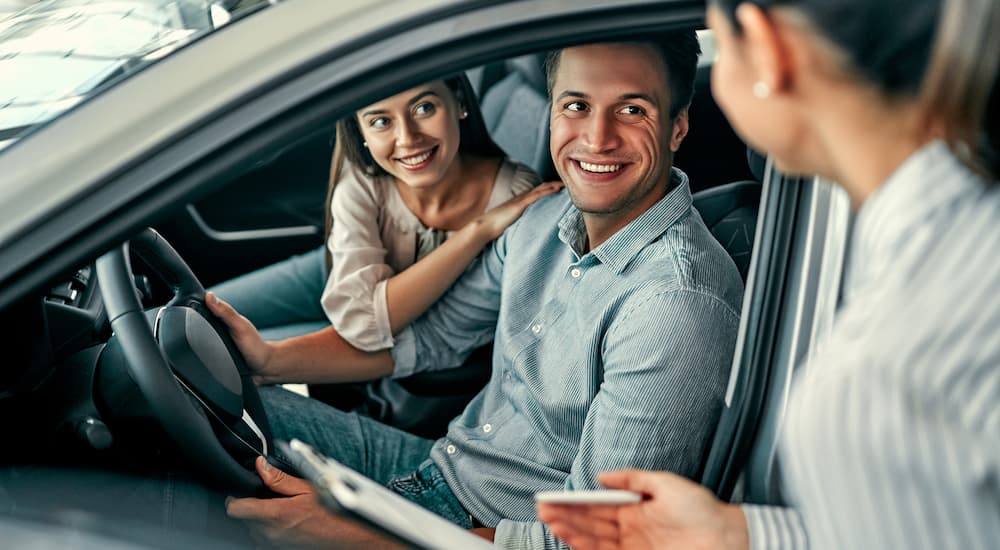 A couple is shown speaking to a saleswoman about how to sell their car.