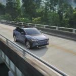 A blue 2023 Subaru Solterra is shown driving over a bridge after visiting Subaru Solterra dealer.