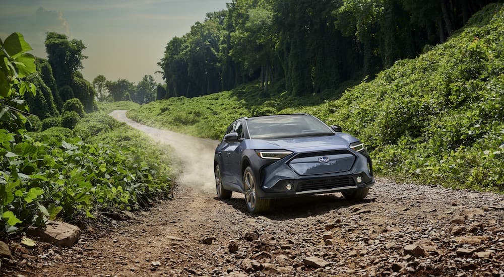 A blue 2023 Subaru Solterra is shown driving on a dirt trail.