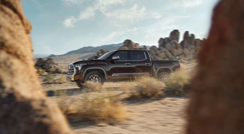 A grey 2022 Toyota Tundra is shown from the side while driving off-road.