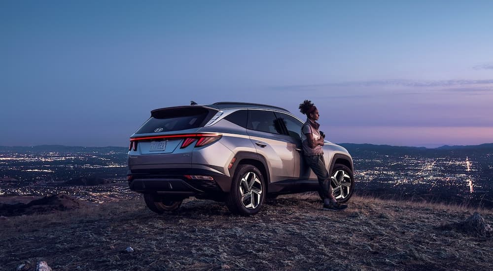 A silver 2022 Hyundai Tucson is shown from the rear overlooking a city skyline.
