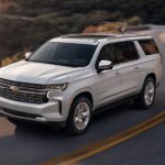 A white 2023 Chevy Suburban is shown from the front at an angle.