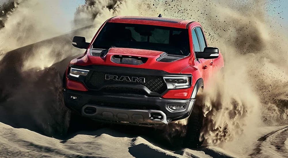 A red 2022 Ram 1500 TRX is shown from the front while driving through sand.