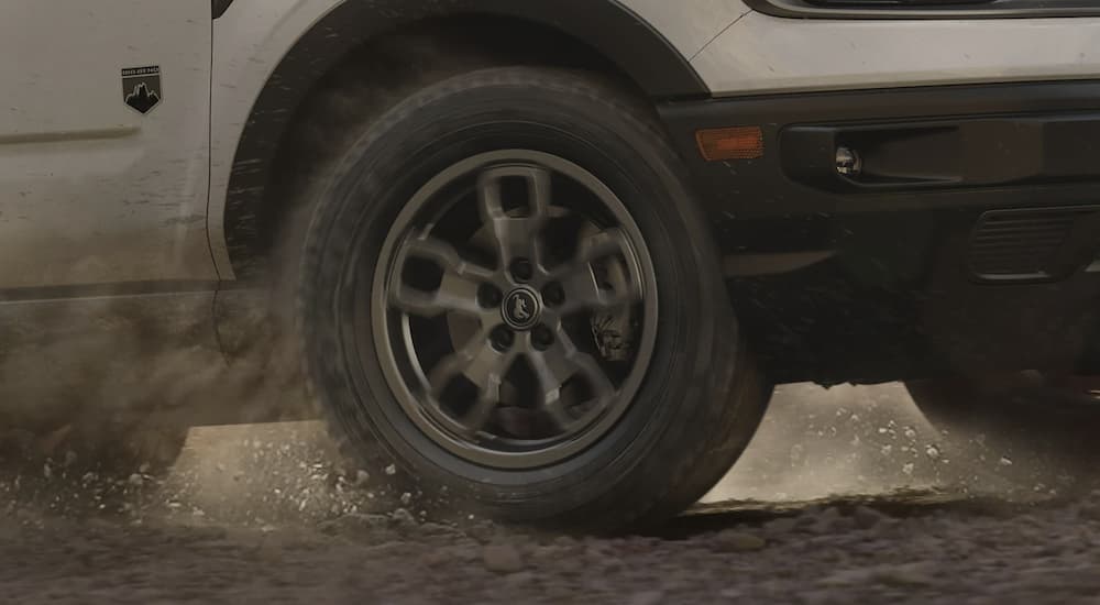 A white 2022 Ford Bronco Sport Big Bend shows the tire kicking up dirt.