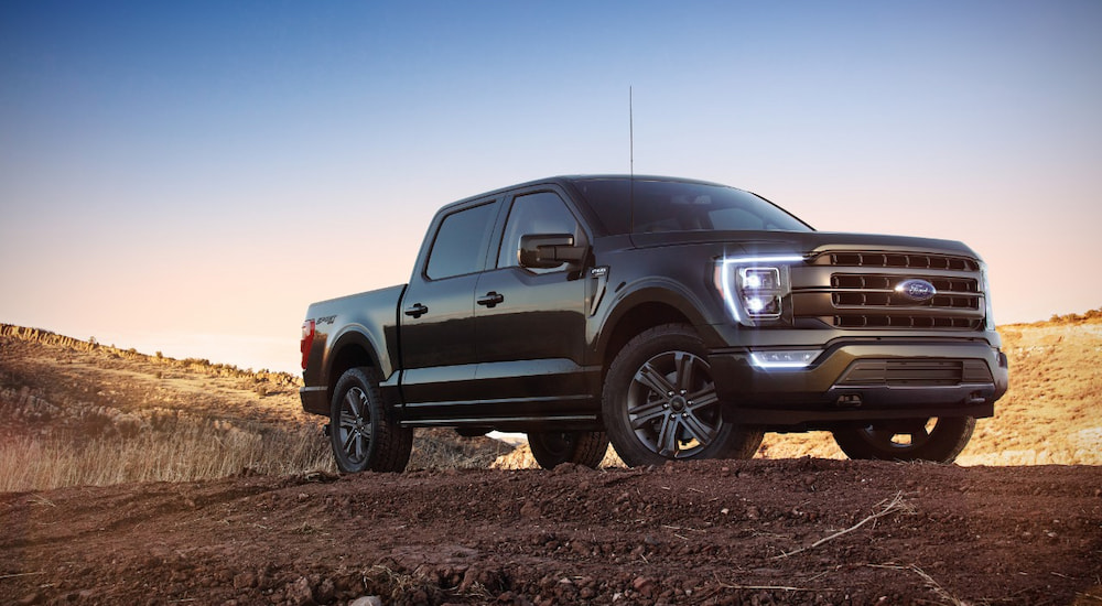 A black 2022 Ford F-150 Lariat is shown parked on a dirt lot.