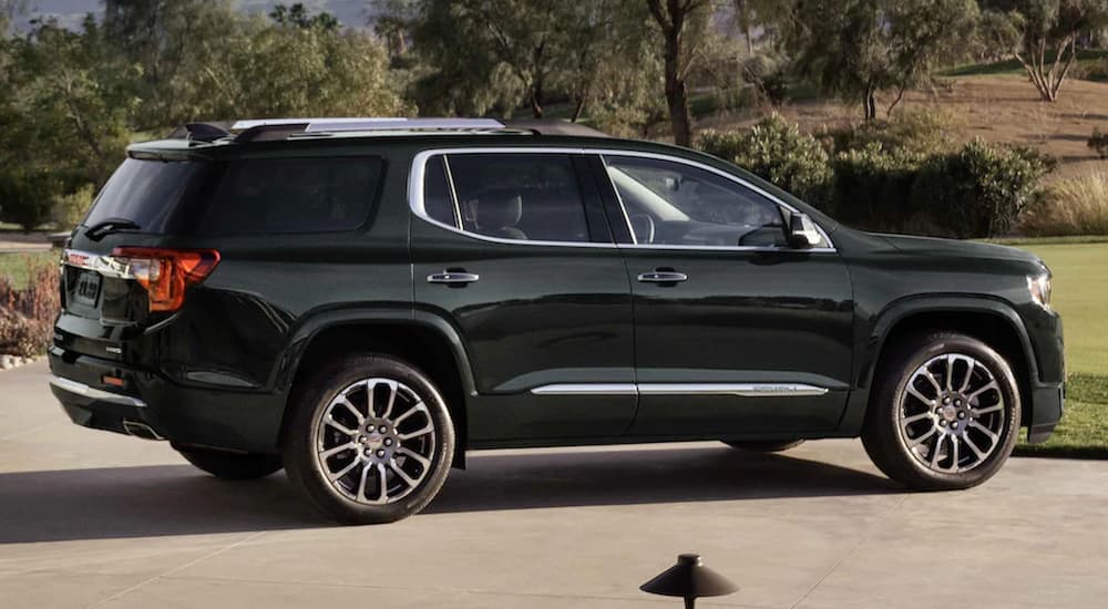 A green 2022 GMC Acadia Denali is shown from the side spark in a lot.