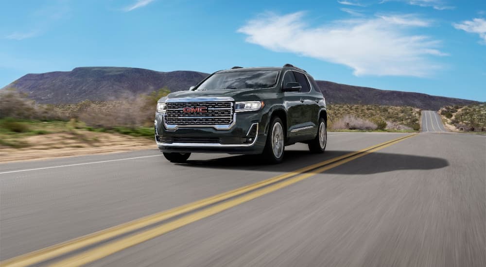 A grey 2022 GMC Acadia Denali is shown driving on an open road.